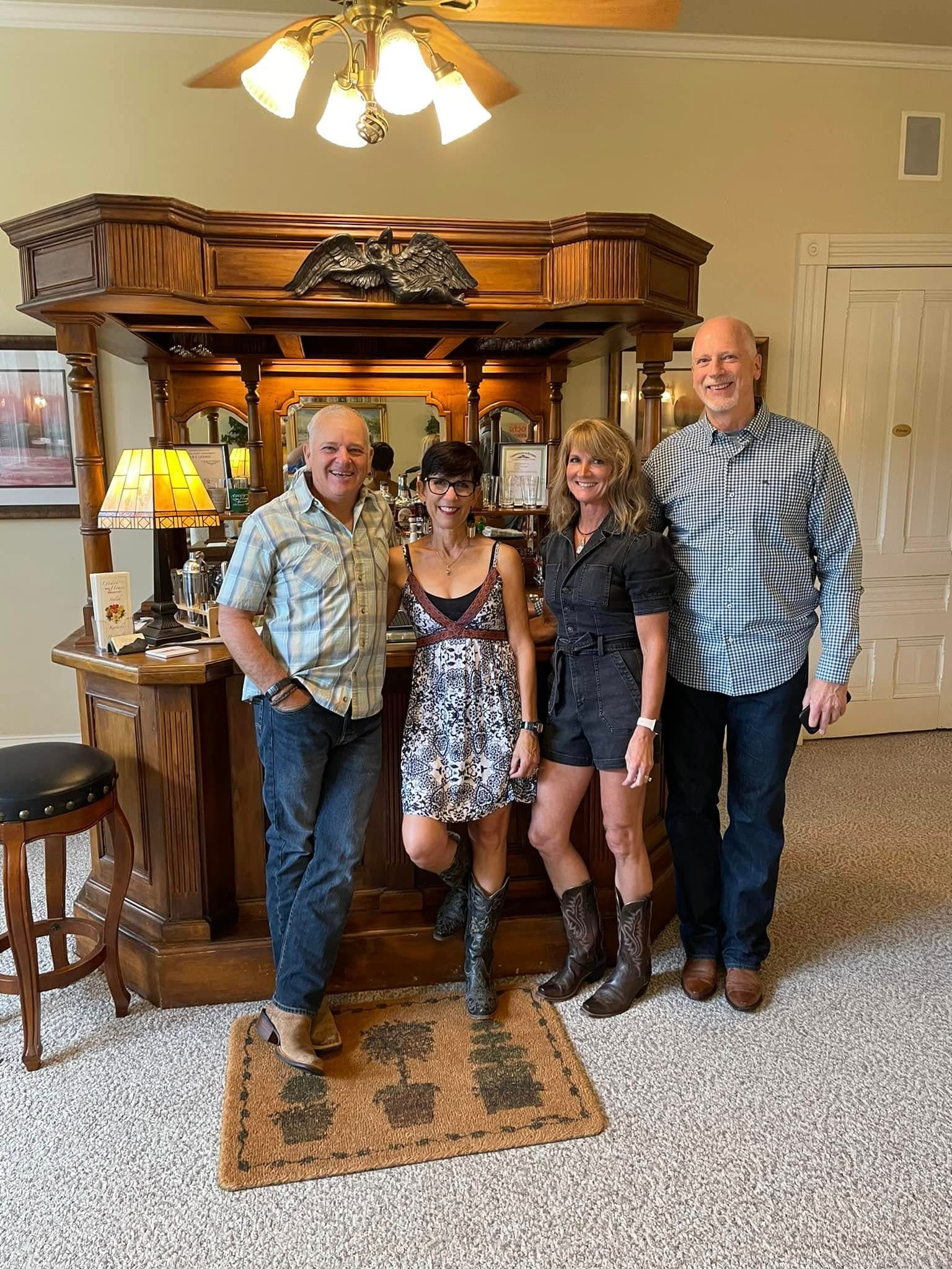Four people posing together in a cozy home bar setting.