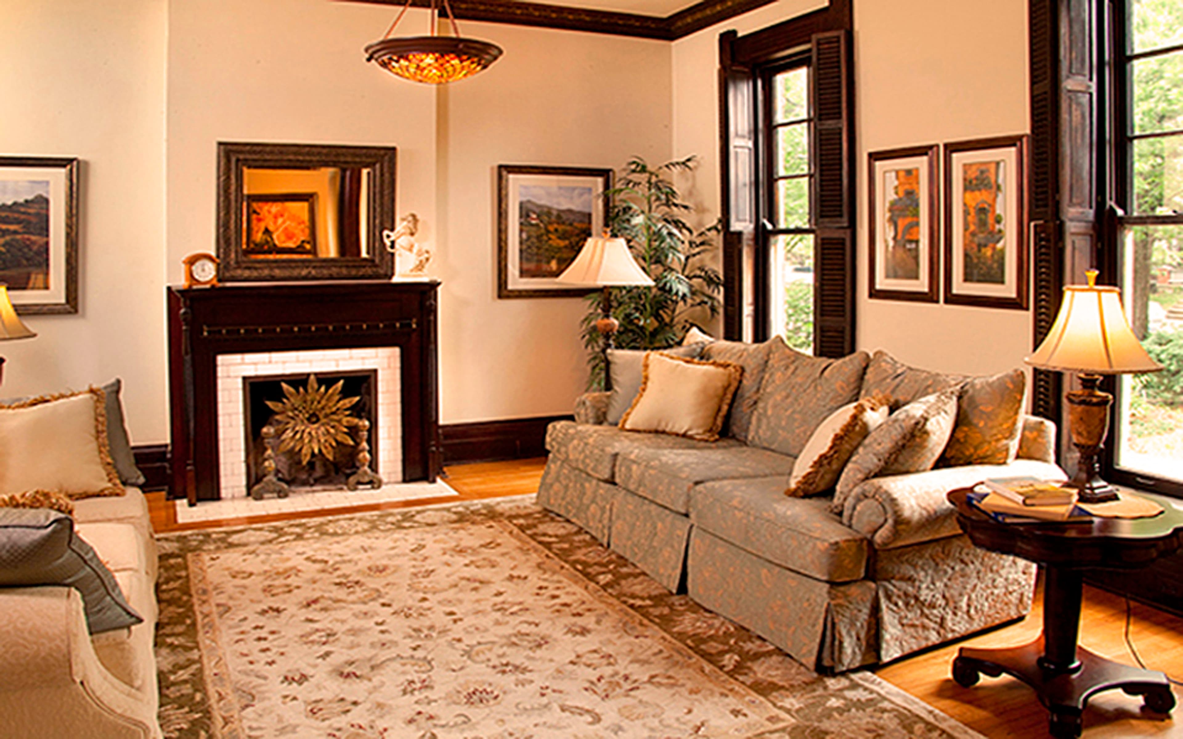 A warmly decorated living room featuring a comfortable couch, a fireplace, and framed artwork on the walls.