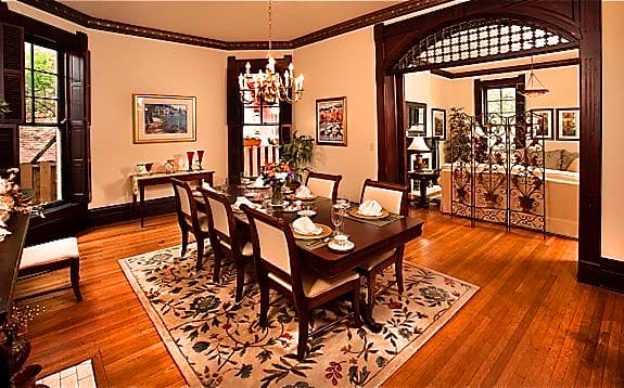 A warmly decorated dining room featuring a wooden table set for a meal, adjacent to a cozy living area.