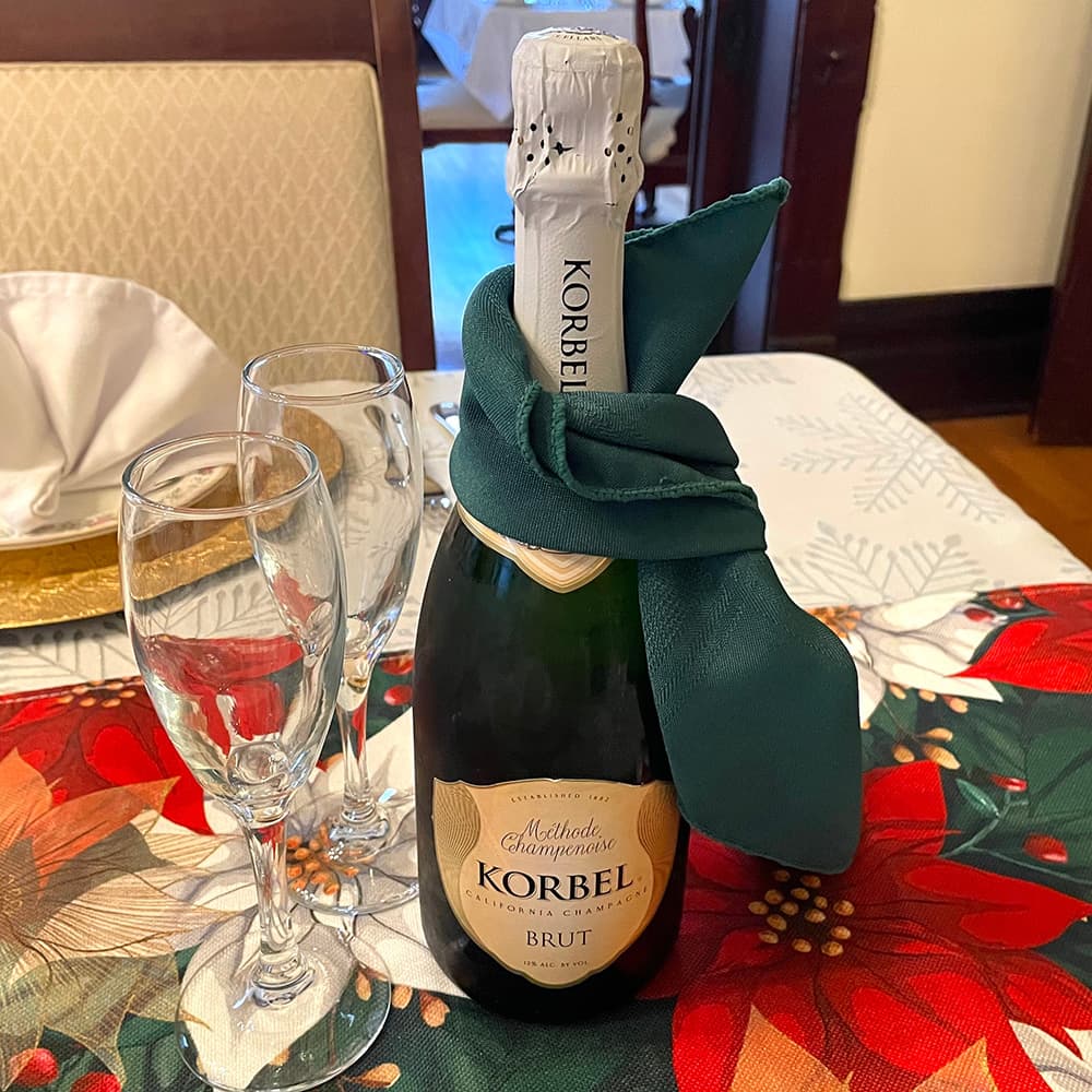 A bottle of Korbel Brut champagne is surrounded by two fluted glasses on a festive tablecloth.