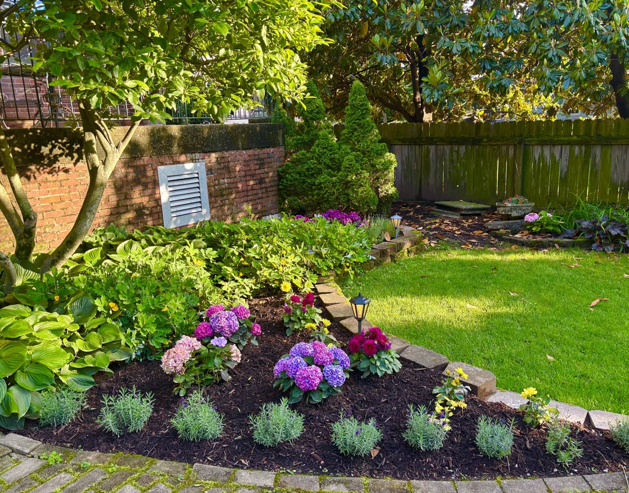 A lush garden featuring colorful flowers, neatly arranged shrubs, and a well-maintained lawn.