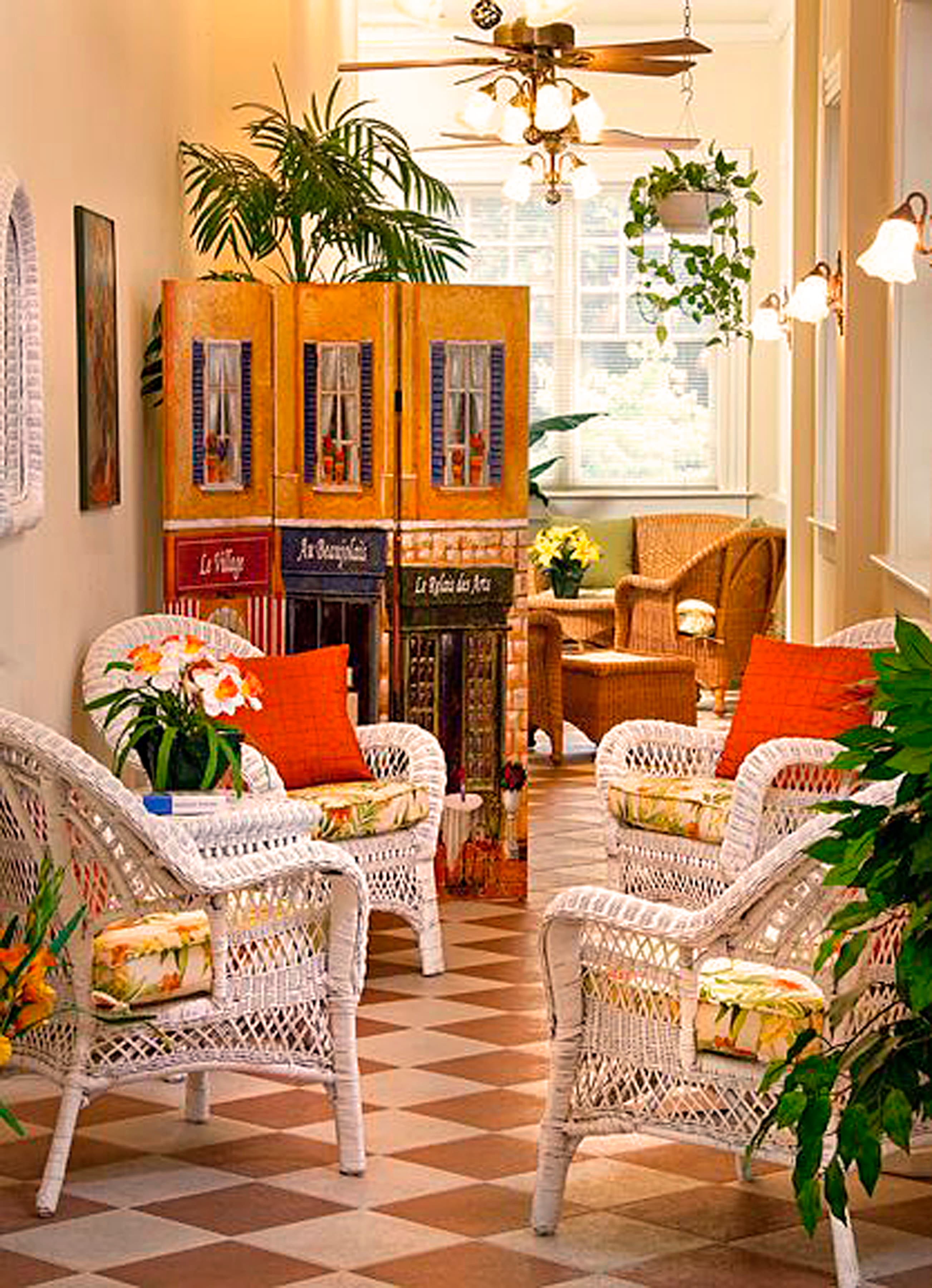 Cozy seating area with white wicker chairs, colorful cushions, and potted plants.