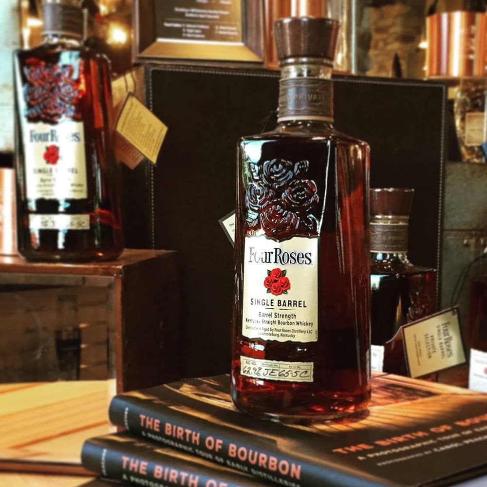 A bottle of Four Roses Single Barrel bourbon sits atop books titled "The Birth of Bourbon."